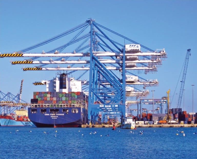 Freight shipping terms. Image of a cargo ship loaded with shipping containers and cranes to unload them.
